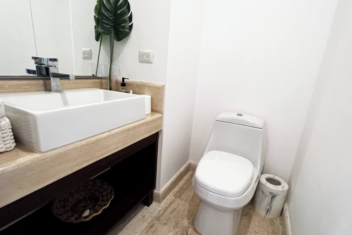 Ein Badezimmer mit Waschbecken, Toilette und einer Pflanze.