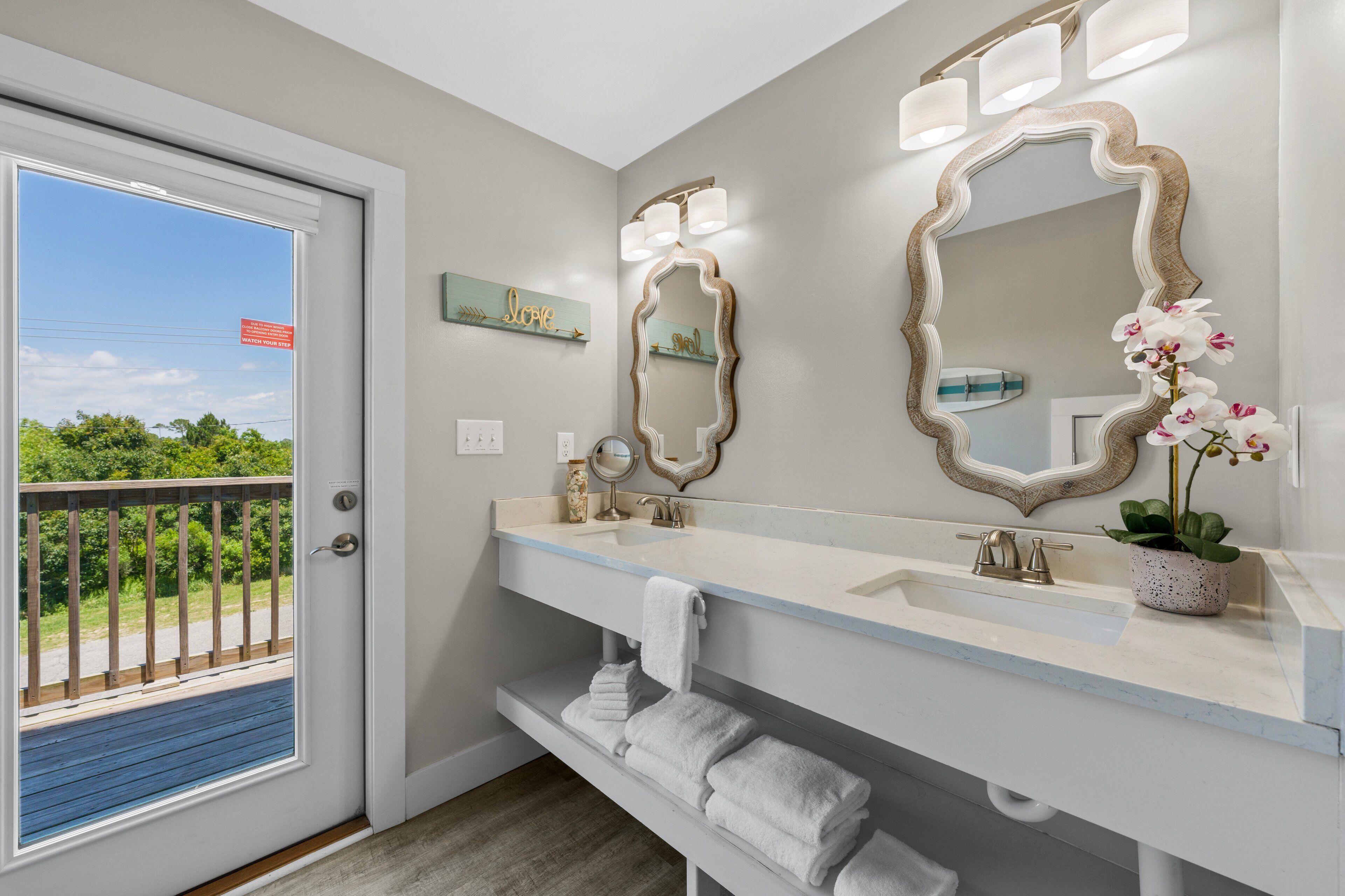 A bathroom with a large mirror, a sink, and a potted orchid.