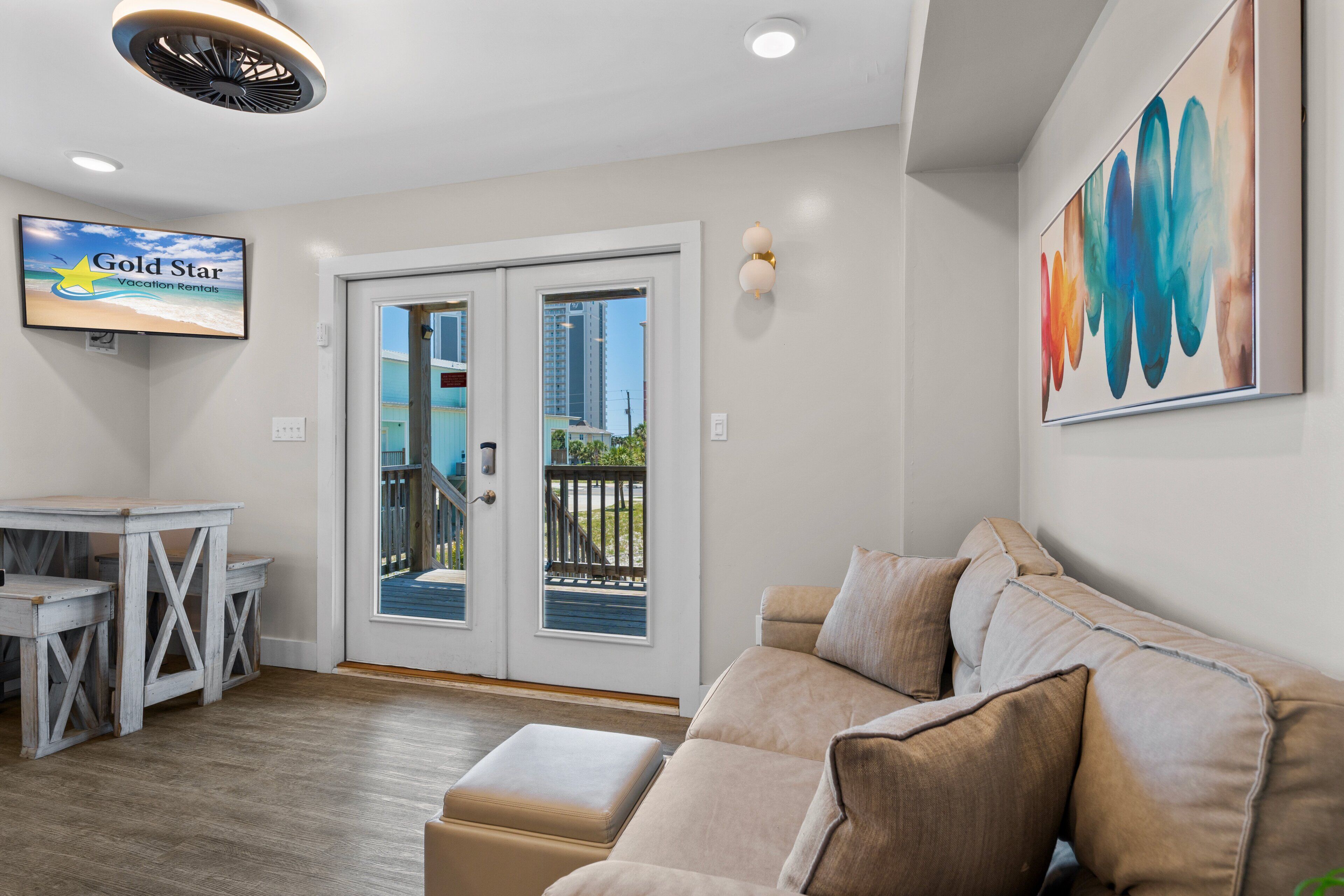 Een moderne woonkamer met een bank, een eettafel en een televisie waarop 'Gold Star Vacation Rentals' staat.