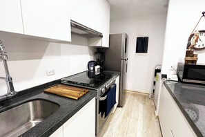 Una cocina compacta con pileta, estufa y refrigerador.