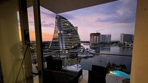 Een balkon met uitzicht op een modern gebouw en een jachthaven.