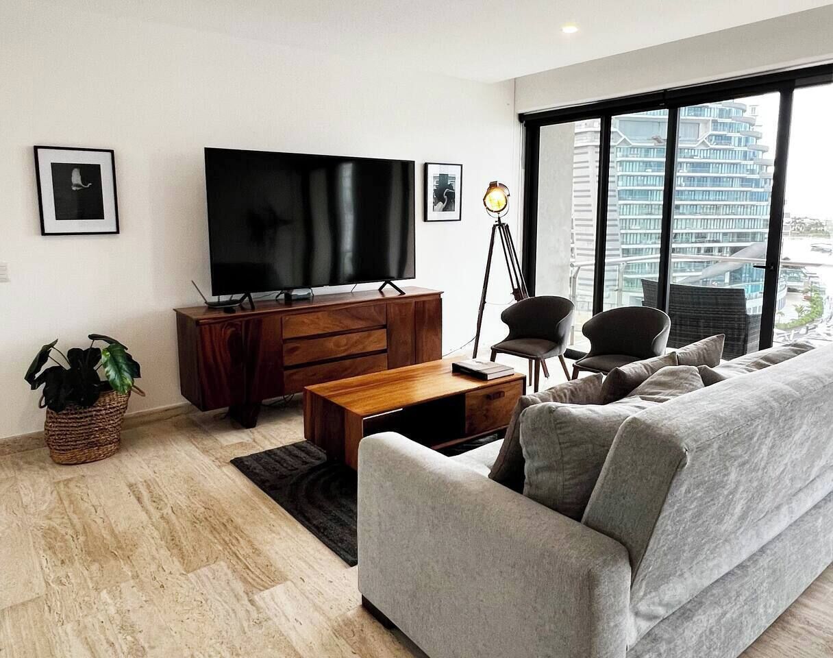 Ein modernes Wohnzimmer mit Sofa, Couchtisch, Fernseher und Stehlampe.