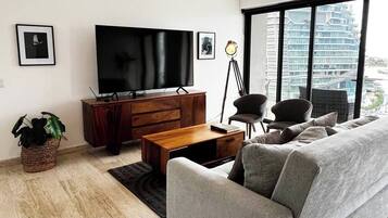 Ein modernes Wohnzimmer mit Sofa, Couchtisch, Fernseher und Stehlampe.