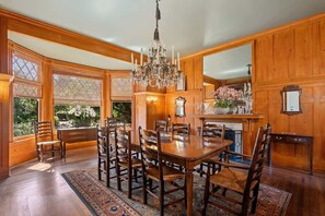A dining room with a wooden table and chairs, a chandelier, and a fireplace. - The Country Manor | Historic Estate (Carpinteria)