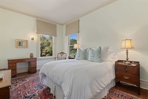 A bedroom with a large bed, a desk, and a nightstand with lamps. - The Country Manor | Historic Estate (Carpinteria)