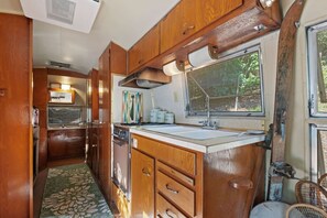 A compact kitchen with wooden cabinets, a sink, and a window providing natural light. - The Country Manor | Historic Estate (Carpinteria)