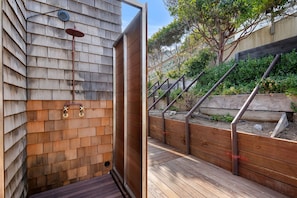 Una terraza de madera con un muro de madera y barandilla de metal.