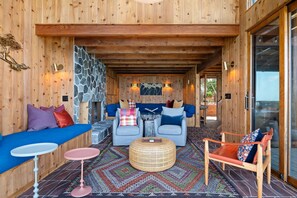 A wooden interior with a stone fireplace, two sofas, a coffee table, and a patterned rug. - Montecito Pointe (Summerland)