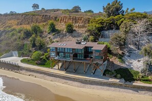 A coastal property with a modern multi-level structure, a beachfront, and a cliffside. - Montecito Pointe (Summerland)