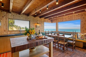 Un interior de madera con zona de comedor, vistas al océano y techo de madera.