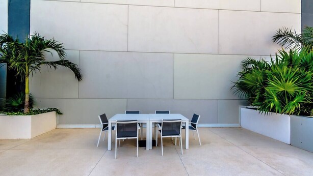 A modern outdoor dining area with a white table and chairs, surrounded by potted plants. - TOP/ 1BR/Luxury Condo/ Ocean/Marina/Canal Views/HZ (Cancún)
