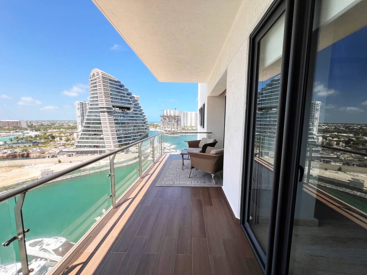 Ein Balkon mit Blick auf ein modernes Kreuzfahrtschiff und einen Yachthafen.