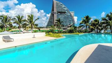 Un hotel con un edificio moderno, piscina y palmeras.