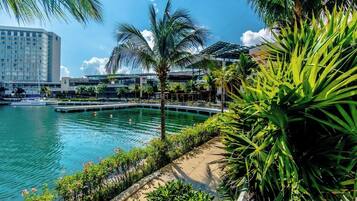 A waterfront hotel with a pool, palm trees, and a view of the city skyline.