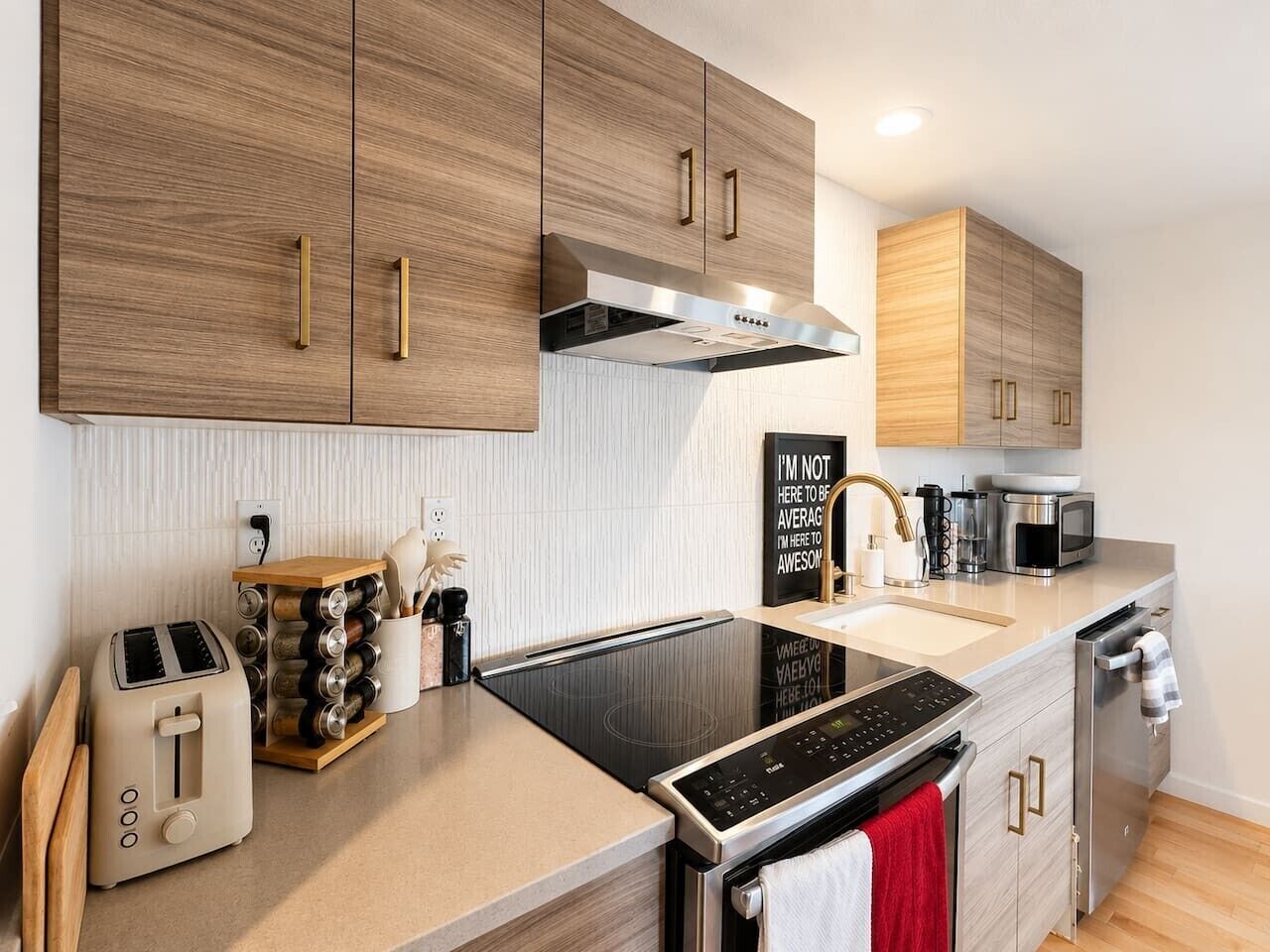 A modern kitchen with wooden cabinets, a built-in oven, a stovetop, and a toaster.