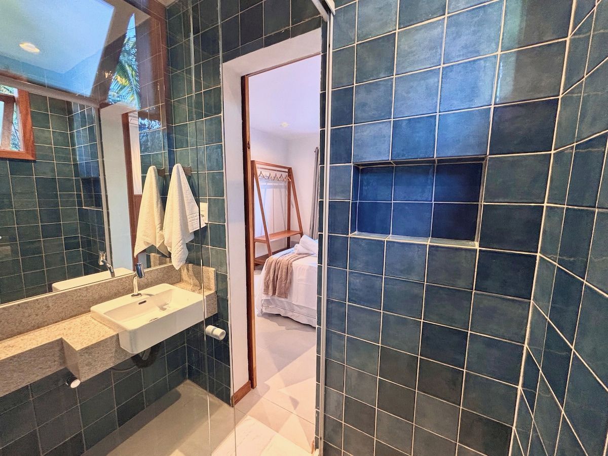 A bathroom with a large mirror, a sink, and a shower area.