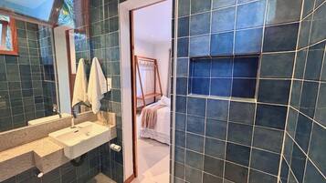 A bathroom with a large mirror, a sink, and a shower area.