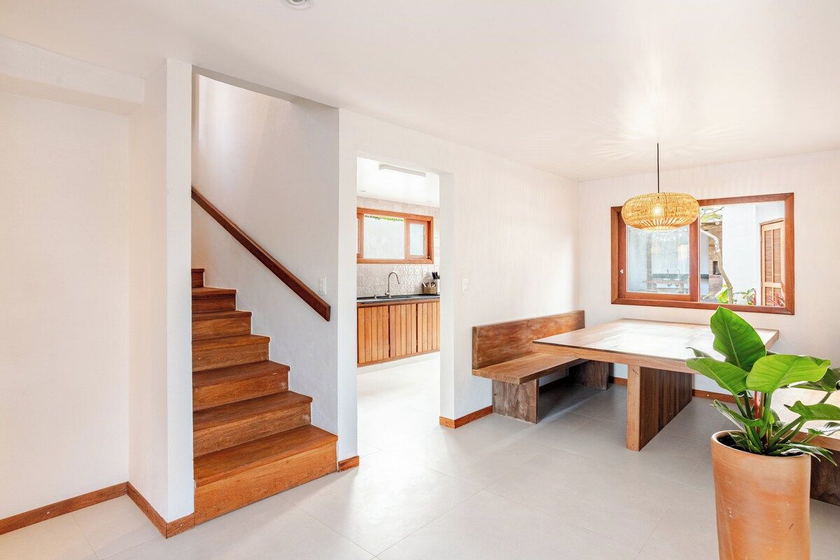 Een modern interieur met een trap, een eethoek met een bank en een keuken op de achtergrond.