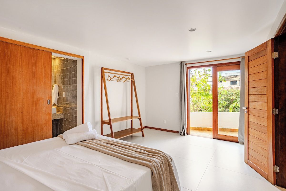 Quarto com cama, guarda-roupa de madeira e varal.