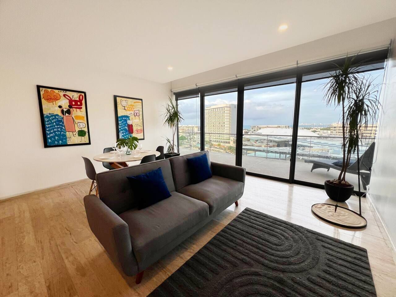 Un salon moderne avec un canapé, une table basse et une grande fenêtre donnant sur la ville.