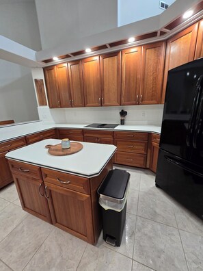 A kitchen with wooden cabinets, a black refrigerator, and a white countertop. - 4/3 fits 10 people w/  Pool, jacuzzi tub, springs  corporate housing welcome! (Crystal River)