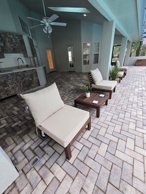A covered outdoor seating area with lounge chairs and a table, a ceiling fan, and a kitchen area with a sink and cabinets. - 4/3 fits 10 people w/  Pool, jacuzzi tub, springs  corporate housing welcome! (Crystal River)