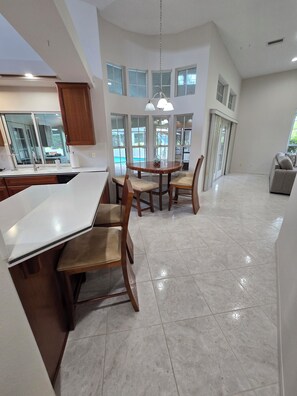 A modern kitchen with a central island, wooden chairs, and a dining table. - 4/3 fits 10 people w/  Pool, jacuzzi tub, springs  corporate housing welcome! (Crystal River)
