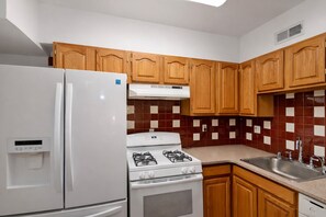 A kitchen with wooden cabinets, a white refrigerator, a stove, and a sink.