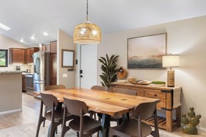 A modern kitchen with wooden cabinets, a stainless steel refrigerator, and a dining area with a wooden table and chairs. - Red Mountain Shadows Retreat: Sleeps 6 in West Sedona Near Hiking Trails, Park & Bike Paths (Sedona)