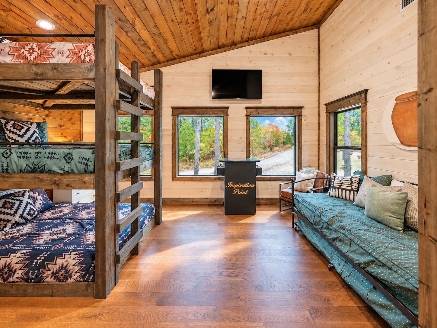 A cabin interior with a loft bed, a sofa, and a desk with a sign reading 'Inspiration Point'.