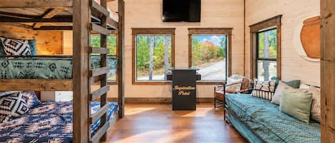 A cabin interior with a loft bed, a sofa, and a desk with a sign reading 'Inspiration Point'.