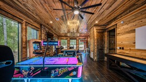 A room with a ping pong table, ceiling fan, and wooden walls.