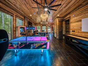 A room with a ping pong table, ceiling fan, and wooden walls. - Heated Pool + Pickleball | Pets | Sauna | Sleep 32 (Broken Bow)