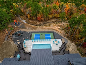 A rooftop with a tennis court, lounge chairs, and a pool. - Heated Pool + Pickleball | Pets | Sauna | Sleep 32 (Broken Bow)