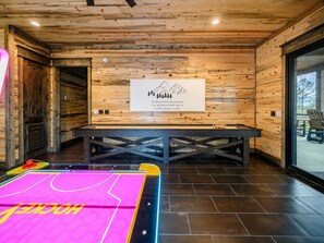 A wooden interior with a table and chairs, a poster on the wall, and a ping pong table.