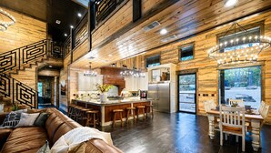 A spacious living area with a brown leather sofa, a dining table with chairs, and a kitchen with a central island.