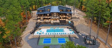 A two-story lodge with a pool and outdoor seating area surrounded by trees.