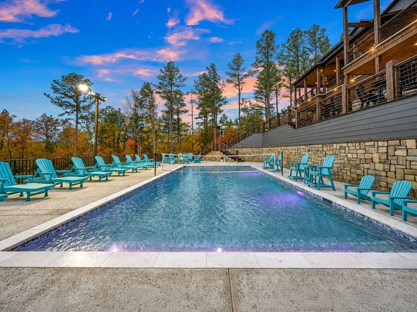 A swimming pool with lounge chairs and a stone wall.