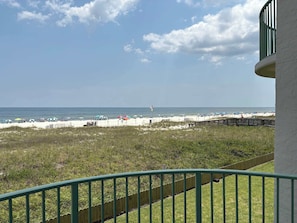 A beach view from a balcony with a wooden fence, a flag, and beach umbrellas. - Perdido Key Paradise Beachfront 3BR (Pensacola)
