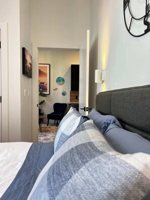 A hotel room with a bed, a desk, a chair, and a wall clock. - Sunrise Surf Suite, Downtown Halifax (Halifax)