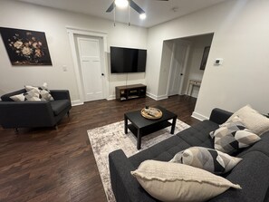 A modern living room with a sofa, coffee table, and a flat-screen TV.