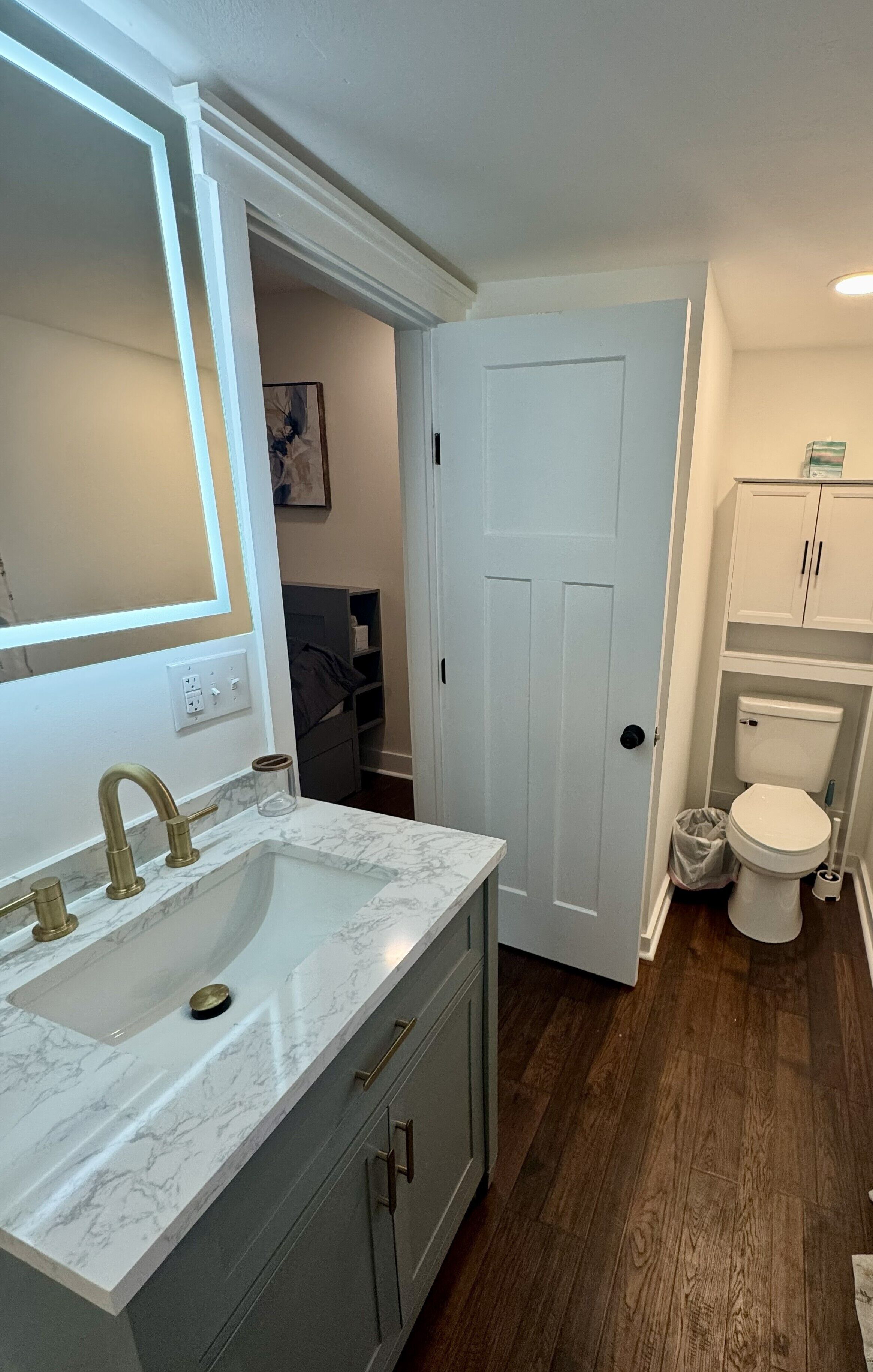 Un bany amb un lavabo blanc, superfície de marbre i un vàter.