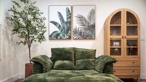 A room with a bed, a wooden cabinet, and two framed botanical prints on the wall.