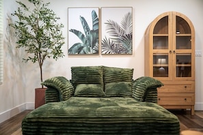 A room with a bed, a wooden cabinet, and two framed botanical prints on the wall.