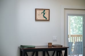A room with a framed map on the wall, a small table with a green cloth and a wooden box, and a door with a view of the outside.