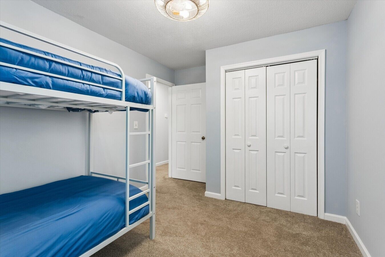 Een kamer met stapelbedden, een deur en vloerbedekking.