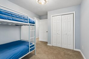 Ein Zimmer mit Etagenbetten, einer Tür und Teppichboden.
