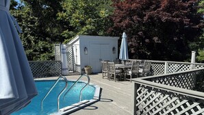 En træterrasse med pool, liggestole og et bord med stole.