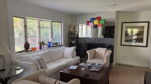 Een woonkamer met een witte bank, een houten salontafel en een open haard.