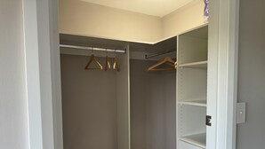 Ein begehbarer Kleiderschrank mit Kleiderstange und offenen Regalen.